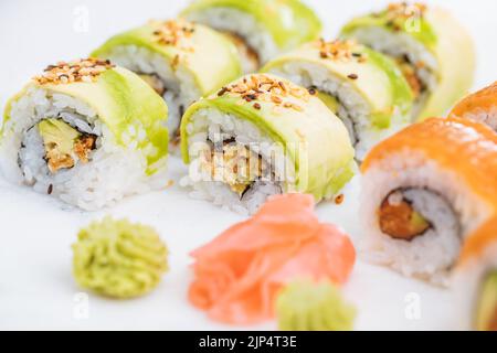 Sushi-Rollen auf Platte, heller Hintergrund. Serviert mit Wasabi und Ingwer. Verschiedene japanische Sushi. Traditionelles Essen. Stockfoto