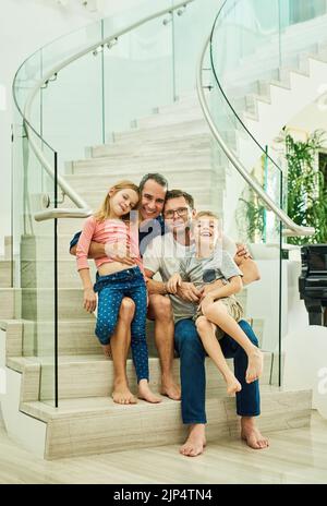 Teilen Sie die Liebe. Ganzkörperportrait einer liebevollen vierköpfigen Familie auf der Treppe zu Hause. Stockfoto