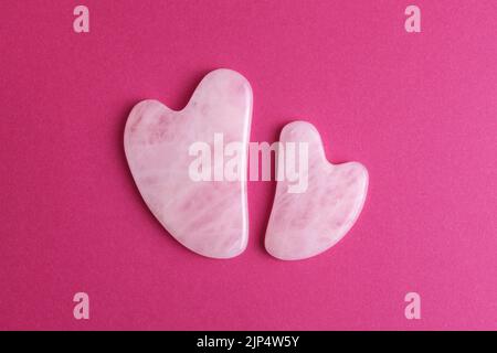Akupressur rosa transparente Gua Sha Massagegeräte unterschiedlicher Größe isoliert auf hellrosa Hintergrund. Draufsicht. Stockfoto