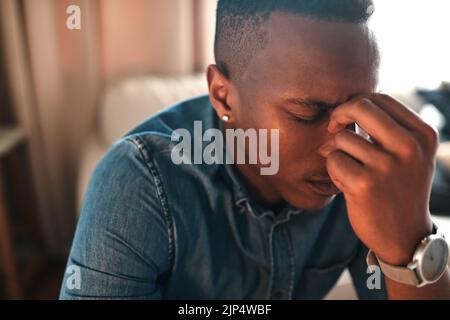 Gestresster, müder Geschäftsmann mit Kopfschmerzen allein zu Hause. Mann mit Augenspannung oder Belastung durch Überarbeiten, Burnout und Angst. Deprimierter Mann Stockfoto