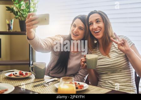 Wochenenden zu Hause mit meiner besten Freundin. Zwei junge Frauen, die morgens zu Hause zusammen frühstücken. Stockfoto