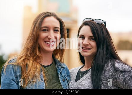 Zwei Erbsen in einer Hülse, die Spaß haben. Portrait von zwei weiblichen besten Freundinnen in einem Vergnügungspark draußen. Stockfoto