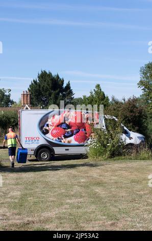 Fahrer, der zum Lieferwagen mit Ekty-Tablett zurückkehrt, Lieferwagen für Tesco nach Hause, Lieferung von Lebensmitteln und Getränken in den Supermarkt im ländlichen Suffolk, England, Großbritannien Stockfoto