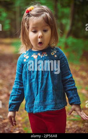 Schönes Baby in einem gestickten Hemd spielen im Wald Stockfoto