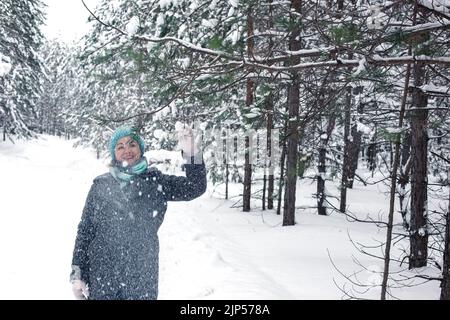 Eine glückliche Frau in einem schneebedeckten Winterwald Stockfoto