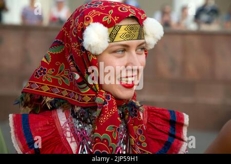 Moskau, Russland. 15. vom August 2022. Eine Frau präsentiert russische Bauerntrachten während des Festivals „Runder Tanz Russlands“ auf dem Platz des VDNKh Exhibition Center vor dem Hintergrund des Zentralpavillons in Moskau, Russland Stockfoto