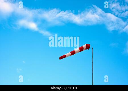 Eine Aufnahme eines rot-weißen Windsocks in einem blauen Himmel Stockfoto