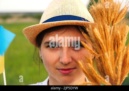 Unschärfe junge ukrainische Frau Porträt. Bouquet von reifen goldenen Dornen aus Weizen auf der Wiese Natur Hintergrund gebunden. Flagge Ukraine. Lächelnd Stockfoto