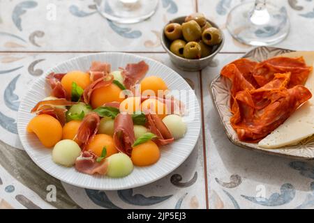 Spanische Tapas, Melone und Schinken, Oliven, Käse und Chorizo Stockfoto