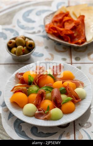 Spanische Tapas, Melone und Schinken, Oliven, Käse und Chorizo Stockfoto