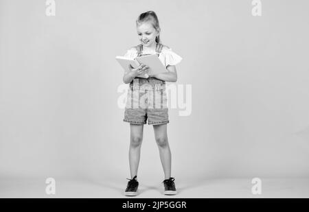 Nettes Kind geht, um Informationen aus dem Buch zu lesen, zurück zur Schule. Stockfoto