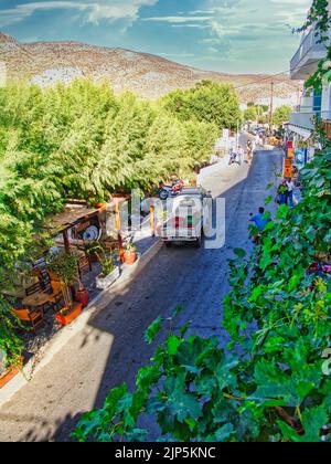 Eine vertikale Aufnahme von Autos, die auf der Straße des schönen Dorfes Kamares auf Kreta, Griechenland, fahren Stockfoto