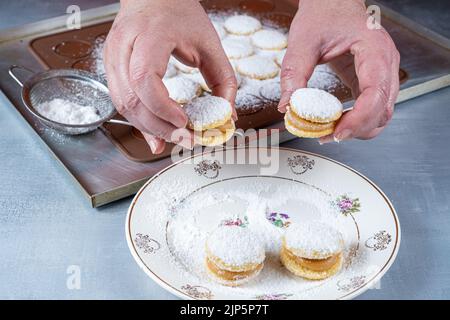 Süßwaren, die zwei süße Leckereien mit bestreutem Zucker und Dulce de leche-Füllung einnehmen. Stockfoto