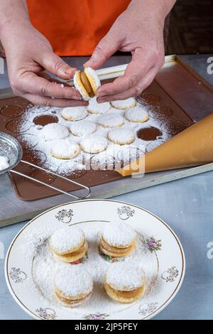 Konditor beendet den süßen Hochzeitsgenuss Dulce de leche mit dem anderen half vertical. Stockfoto