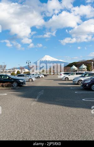 Fuji-Stadt, Shizuoka, Japan - 2. Februar 2020: Wunderschönes Stadtbild mit dem Berg Fuji. Autos auf öffentlichen Parkplätzen. Blauer Himmel am Morgen mit weißen Wolken. Stockfoto