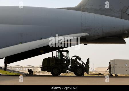 Ein 10K All-Terrain-Gabelstapler befördert eine General Atomics MQ-9 Reaper Drohne in Richtung einer Lockheed C-5M Super Galaxy, die dem 22. Airlift Squadron am 10. August 2022 auf dem Al Dhafra Air Base, Vereinigte Arabische Emirate, zugewiesen wurde. Die Schnitter können in „Särge“ genannte Lagerbehälter zerlegt werden, um sie schnell wieder zu verstauen. (USA Air Force Foto von Tech. Sgt. Jeffrey Grossi) Stockfoto