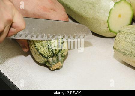 Rezept für Zucchini-Krapfen. Schritt 1 - die Zucchini schälen. Die Hände schälen grüne Zucchini mit einem Gemüseschäler. Stockfoto