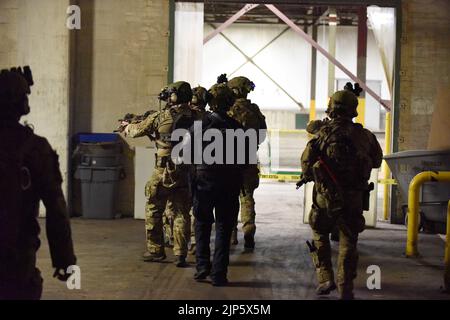 Mitglieder eines Einsatzteams, bestehend aus einer Operational Detachment Alpha (ODA), einem 1. Bataillon, einer 20. Special Forces Group (Airborne), der Massachusetts Army National Guard, der Battle Creek Police Department (MI), der Illinois State Police, Und andere Agenturen führen während einer gemeinsamen Trainingsübung, Battle Creek, Michigan, 10. August 2022, eine Gebäudesuche nach Gegnern durch. Während des Nordstreiks 22-2, nahmen etwa 7.400 Teilnehmer aus 19 Staaten und mehreren Koalitionsländern, darunter Kanada, Lettland und dem Vereinigten Königreich, an der Schulung Teil, um die Bereitschaft der gemeinsamen und Reservetruppe zu bestätigen. Stockfoto