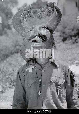 Schwarz-Weiß-Fotografie eines Tänzers, der eine Maske trägt, während des Diablos Danzantes del Yare (Dancing Devils of Yare), einem religiösen Fest, das in San Francisco de Yare im Bundesstaat Miranda am Fronleichnamsfest in Venezuela, Südamerika, gefeiert wird Stockfoto