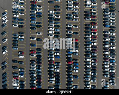 Eine direkte Luftaufnahme über einem Parkplatz mit neu hergestellten Autos, außerhalb eines Produktionswerks. Stockfoto