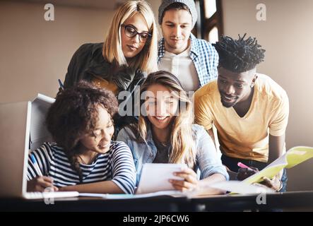 Gemeinsam Notizen machen. Eine Gruppe von Studenten, die gemeinsam im Unterricht an einer Aufgabe arbeiten. Stockfoto