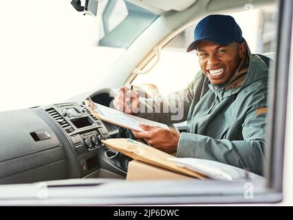 Ich werde bald mit deiner Lieferung vorbei kommen. Portait eines Kuriers, der in einem Lieferwagen auf ein Klemmbrett schreibt. Stockfoto
