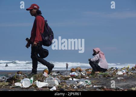 Touristen spielen am schmutzigen Parangkusumo-Strand in Yogyakarta, Indonesien Stockfoto