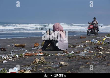 Touristen spielen am schmutzigen Parangkusumo-Strand in Yogyakarta, Indonesien Stockfoto