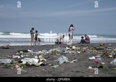 Touristen spielen am schmutzigen Parangkusumo-Strand in Yogyakarta, Indonesien Stockfoto