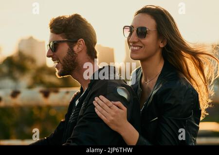 Entdecken Sie mit Ihrem Geliebten. Ein junges, attraktives Paar, das mit einem Roller durch die Stadt fährt. Stockfoto