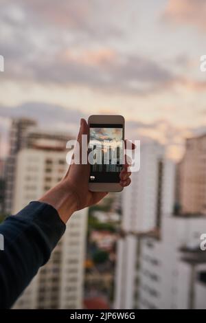 Der perfekte Ort, um ein paar Aufnahmen zu machen. Ein unkennbarer Mann, der draußen mit seinem Handy ein Foto von der Stadt machte. Stockfoto