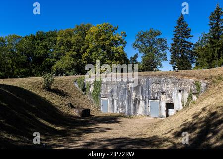 10. August 2022, Frankreich, Mutzig: Die Eingangstüren eines Bunkers sind zwischen bewachsenen Hügeln zu sehen. Der Komplex 'Feste Kaiser Wilhelm II.' mit unterirdischen Kasernen und Korridoren, der 1893 während des Deutschen Reiches erbaut wurde, soll vom französischen Militär an den örtlichen Gemeindebund verkauft werden. Letzteres will die bisher provisorischen Einrichtungen für die Besucher verbessern. Ein lokaler Verein ist für die Besucherbetreuung zuständig - aber nach der Corona-Krise bleiben Gäste aus dem benachbarten Deutschland fern. (Zur dpa 'Verein will mehr Besucher aus Deutschland am Kaiserfest') Foto: Philipp Stockfoto