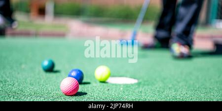 Minigolf-Spiel mit mehreren farbigen Kugeln in der Art eines Putter aufgereiht. Stockfoto