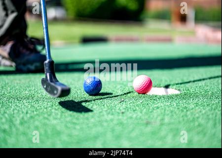 Minigolf-Spiel mit mehreren farbigen Kugeln in der Art eines Putter aufgereiht. Stockfoto