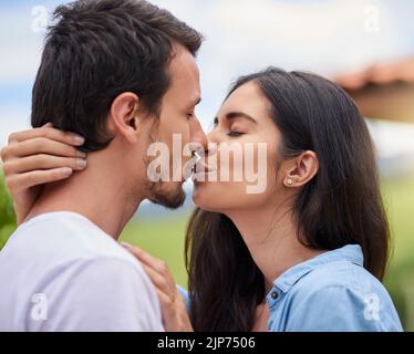 Küsse mich, als ob du mich vermisst. Ein liebevolles junges Paar, das sich im Freien küsst. Stockfoto