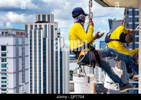 Thailändische Arbeiter reparieren die Fenster des Hochhauses über Bangkok, Thailand Stockfoto