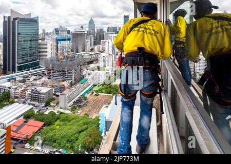 Thailändische Arbeiter reparieren die Fenster des Hochhauses über Bangkok, Thailand Stockfoto