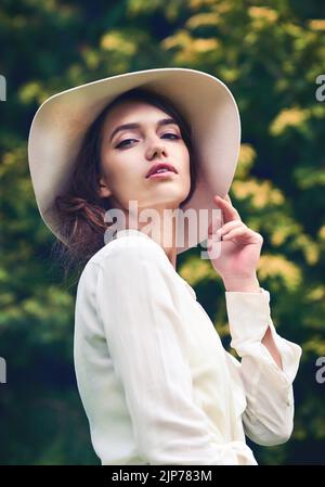 Ihre Schönheit ist total hypnotisierend. Porträt einer attraktiven jungen Frau, die einen stilvollen Hut im Freien trägt. Stockfoto