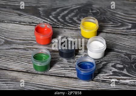 Gouache-Set. Farbdosen öffnen. Auf Kiefernbrettern. Nahaufnahme. Stockfoto