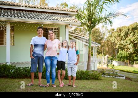 Das Leben kann viele Dinge sein, aber die Familie macht es wahr. Porträt einer glücklichen jungen Frau, die zusammen mit ihrer Tochter und ihren Söhnen in ihrem Hinterhof steht. Stockfoto