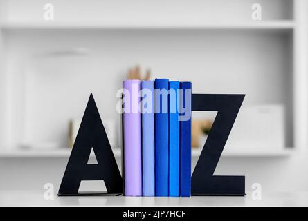 Stilvoller Halter mit Büchern auf dem Tisch im Zimmer Stockfoto