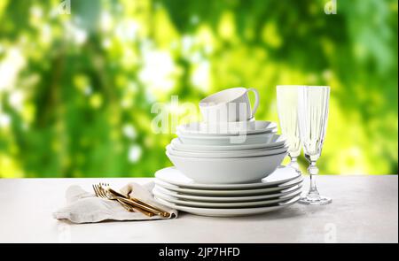 Set von sauberen Geschirr mit Besteck auf weißem Tisch im Freien Stockfoto