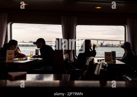 Osaka, Japan - 27. November 2018: Touristen in Silhouette auf dem Tisch im Schiff Santa Maria, die während der Kreuzfahrt um die Bucht von Osaka reden und trinken. Stockfoto