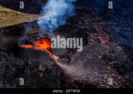 Magma fließt aus einem herzförmigen Krater am Vulkan im Fagradalsfjall, Island, nach einem Ausbruch aus einer neuen Spalte auf der Halbinsel Reykjanes, etwa 35 Meilen von der Hauptstadt Reykjavic entfernt, der Ausbruch findet seit dem 3.. August 2022 statt. Bilddatum: Montag, 15. August 2022. Stockfoto