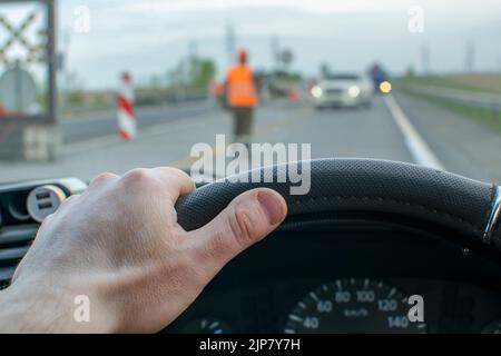 Die Fahrerhand ist am Lenkrad, das entgegenkommende Autos übersteht und übersteht Stockfoto