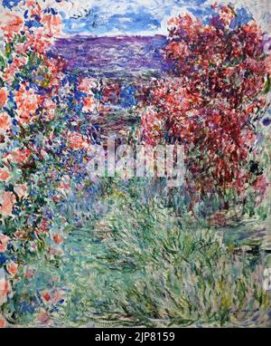 Das Haus zwischen den Rosen (1925) von Claude Monet (1840-1926). Zeigt einen üppigen Gartenweg, der von lebendigen blühenden Rosensträuchern in Giverny gesäumt ist. Stockfoto