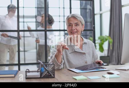 Moderne reife Geschäftsfrau, die an ihrem Schreibtisch arbeitet Stockfoto