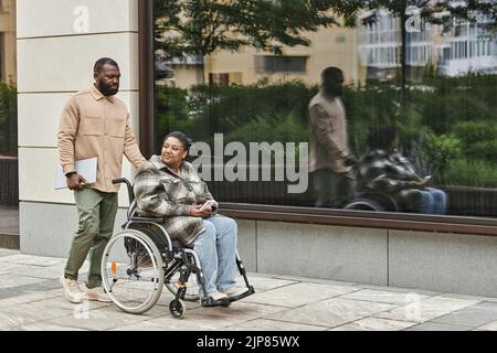 In voller Länge Porträt des modernen schwarzen Paares mit Partner im Rollstuhl im Freien in der Stadt Einstellung, kopieren Raum Stockfoto