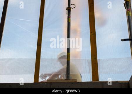 Ein österreichischer Arbeiter auf der Baustelle in Aktion trägt einen Schutzhelm Stockfoto