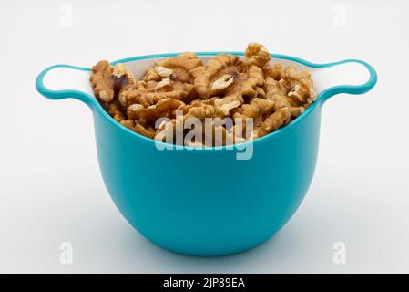 Haufen Walnüsse in einer blauen Kunststoffschale isoliert auf weißem Hintergrund. Stockfoto